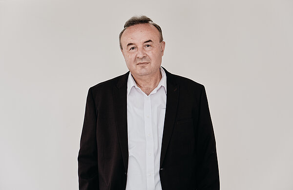 Das Foto zeigt Andreas Schardt, den Geschäftsführer der Katholischen Sozialstation, in schwarzem Jacket vor neutralem Hintergrund. 